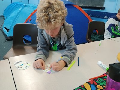 This Cub is sitting quietly, concentrating on the intricate design he's making on his paper skull. His leaders have never seen him so still or quiet!