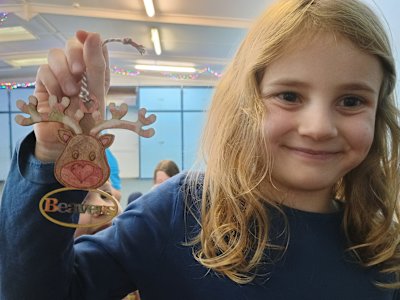 With a big smile on her face, this Beaver is showing off her wooden reindeer decoration that she's coloured in. It looks lovely, with stripy candy cane antlers!