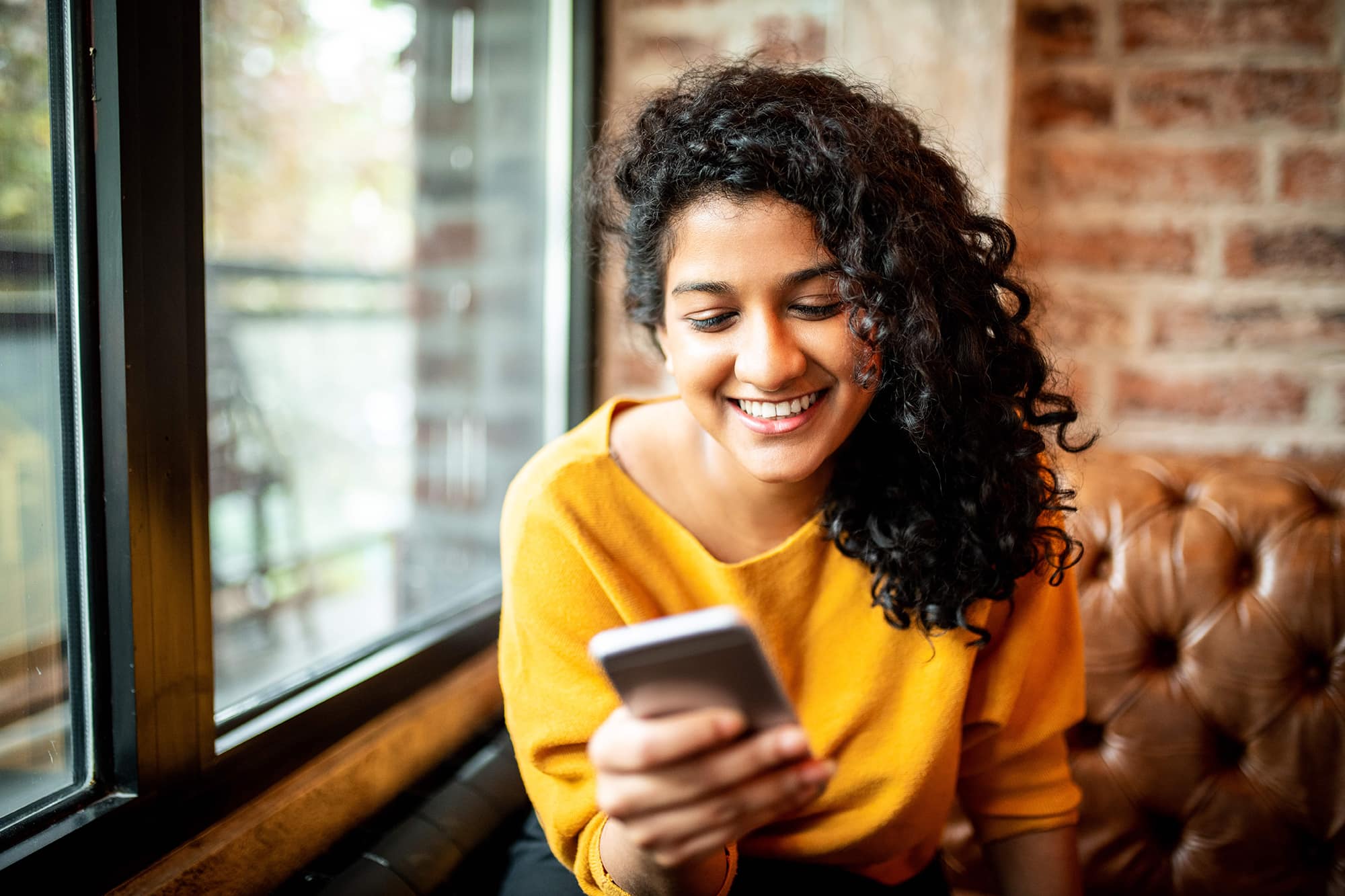 A woman using her phone while smiling big. 