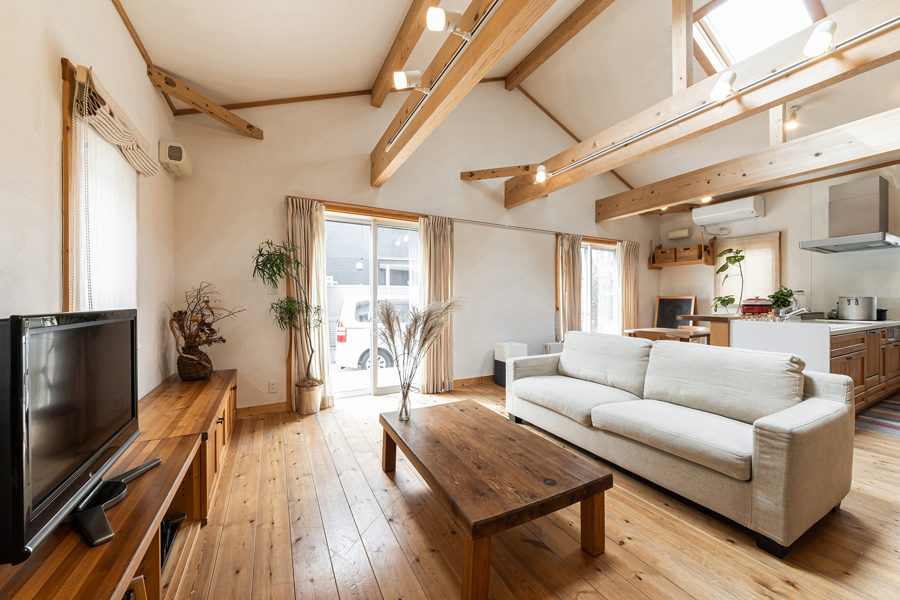 A look inside a living room with a beige couch and beautiful brown hard wood floors. 