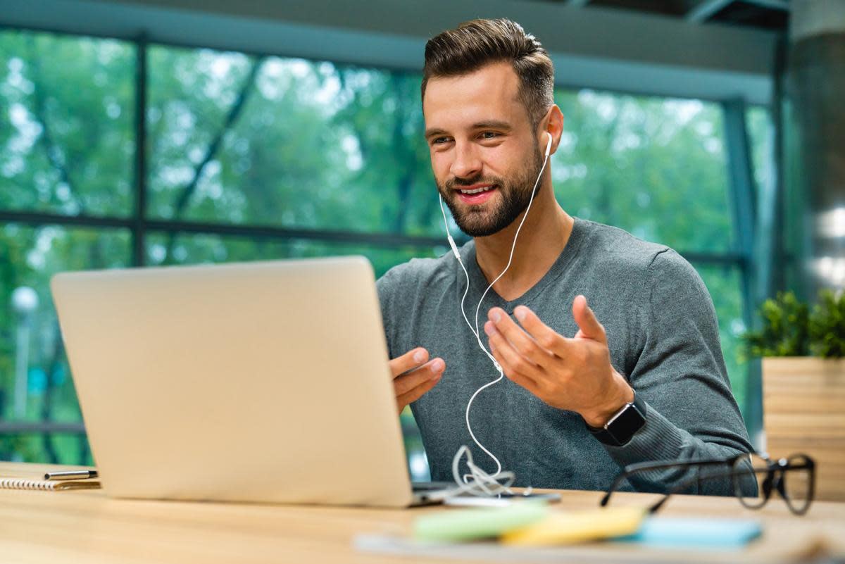 A man looking at a laptop and gesturing