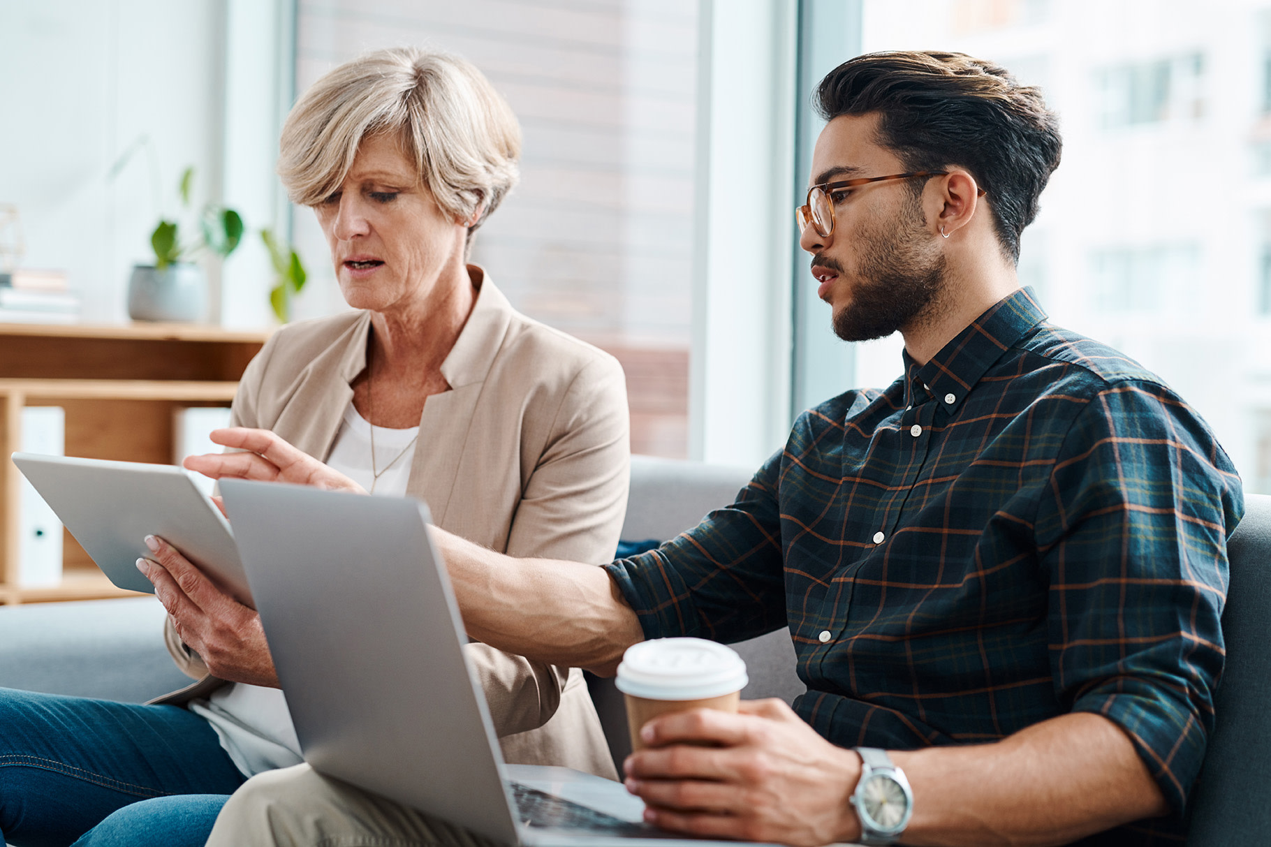 A man helping a woman with her tablet. 