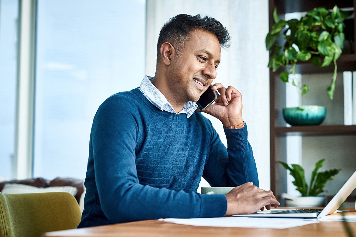  A man on his computer on the phone. 