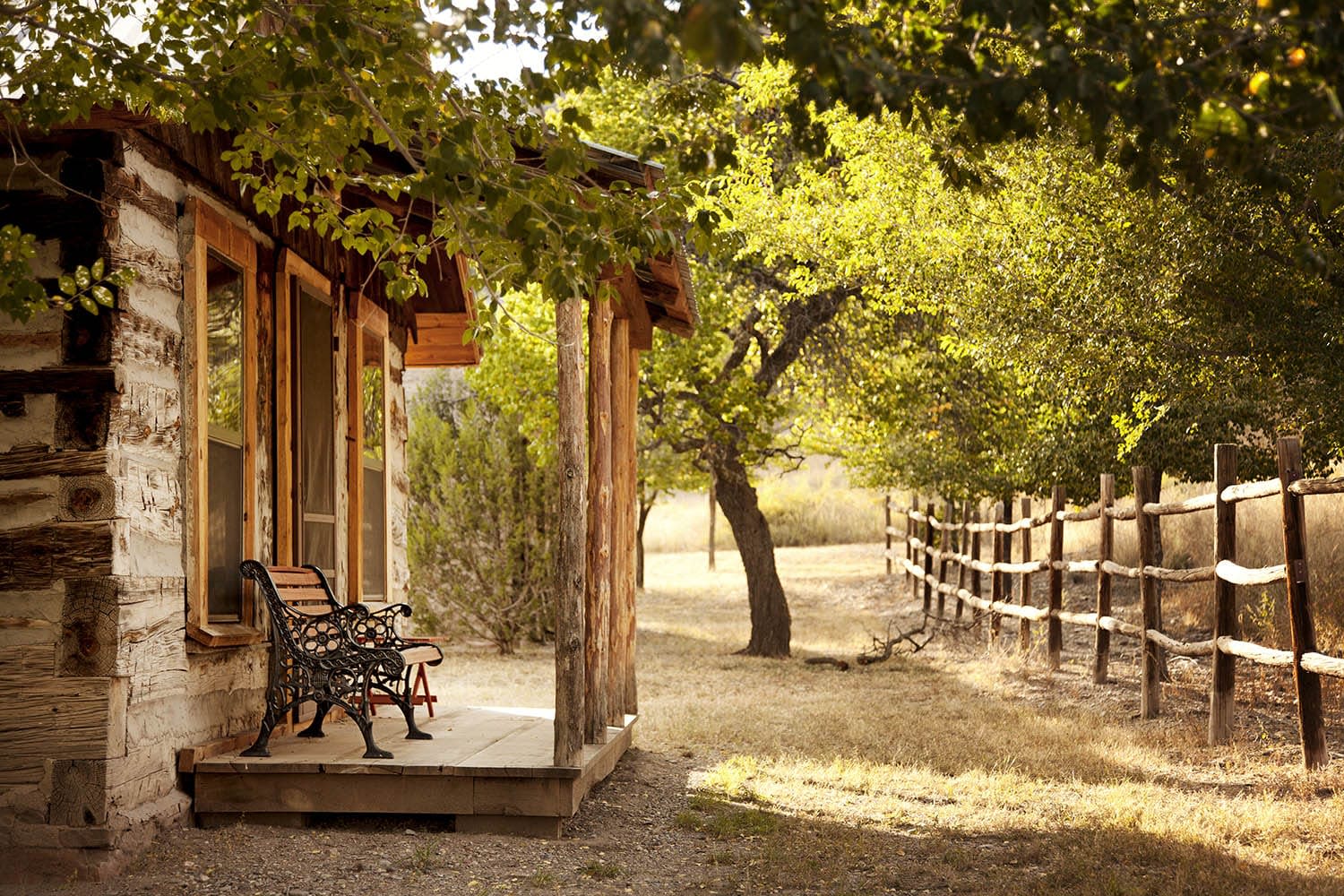 Porch of a wooden house with a bench and gate in front the house.