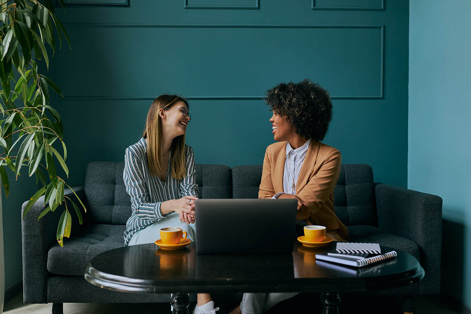 Two women sitting on a couch, talking