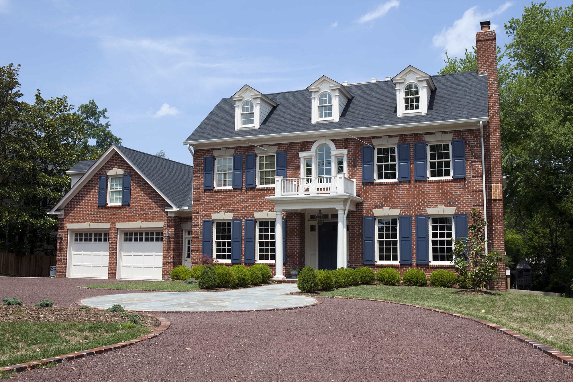 The front view of a house with red brick and blue shutters. 