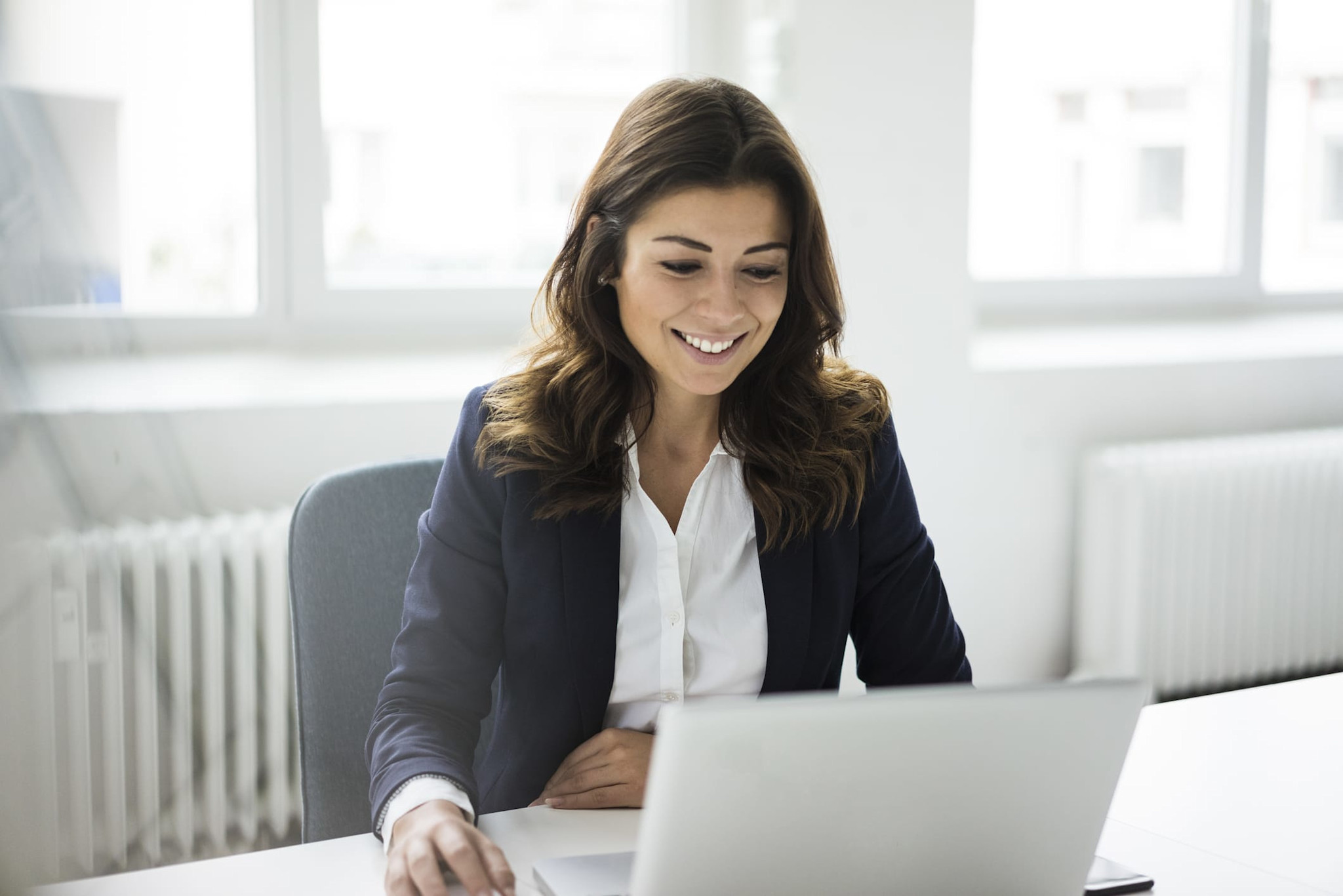 A woman smiling at her computer. 