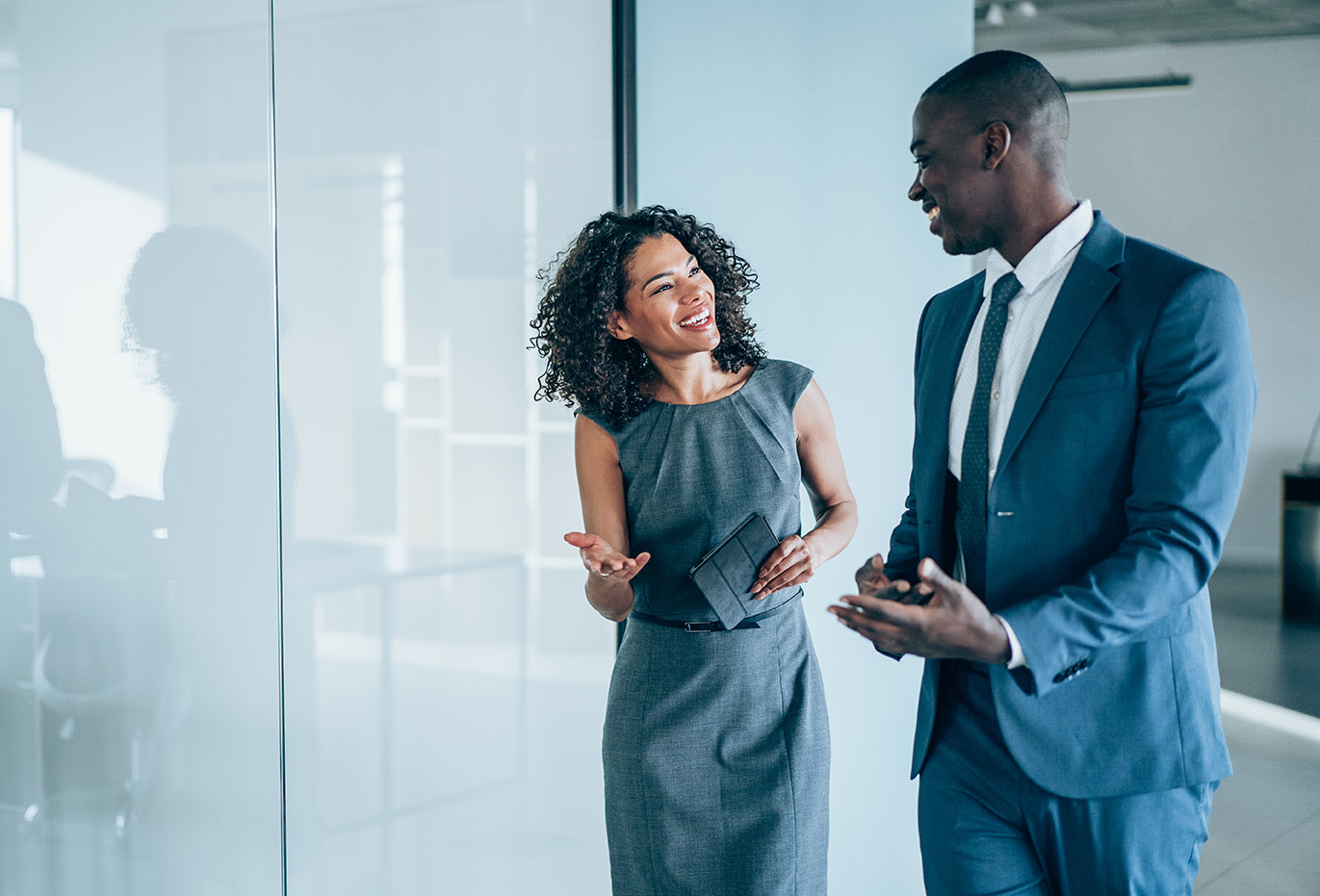 A man and woman smiling at each other while discussing something. 