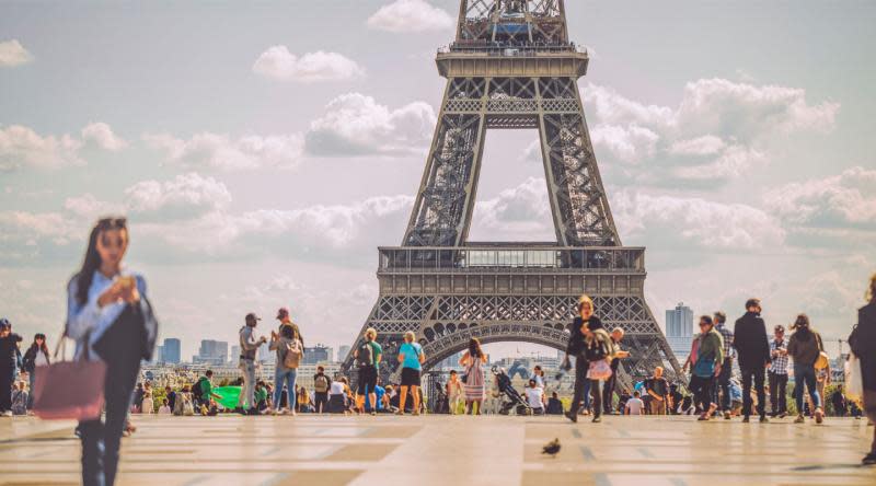 An image of the Eiffel Tower with people walking nearby