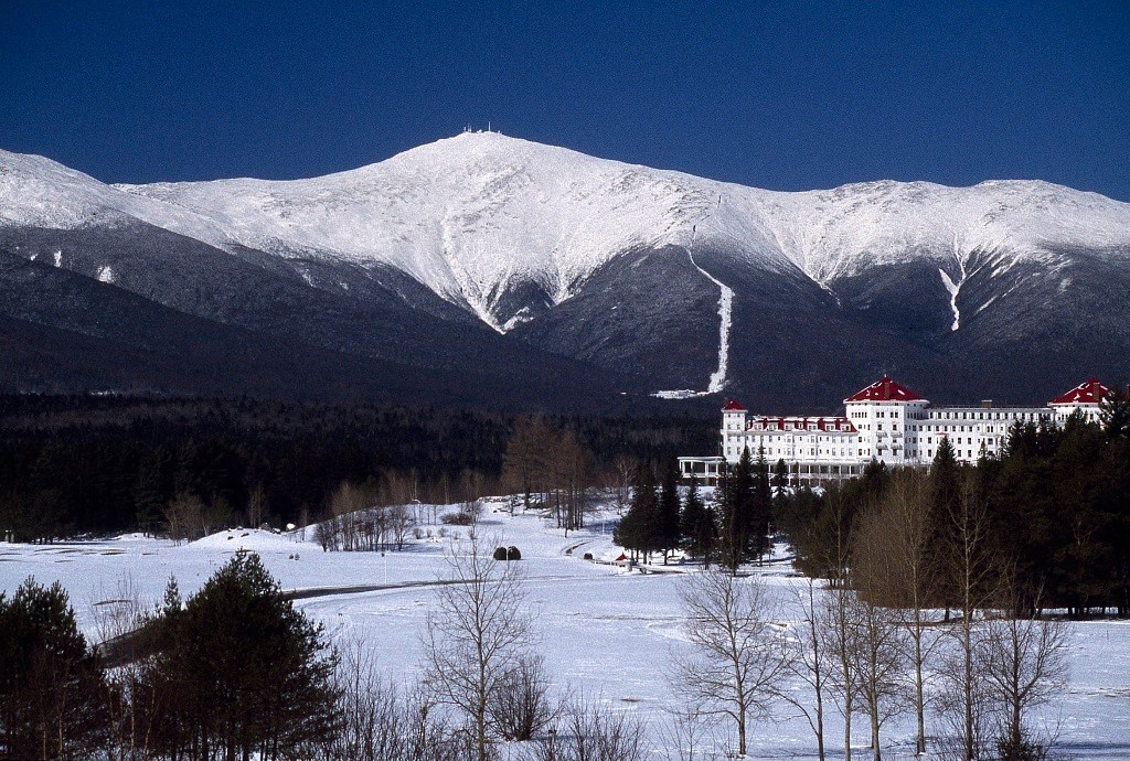 The Omni Mount Washington Resort in the distance with snow covering the ground as well as the mountain tops in the background.