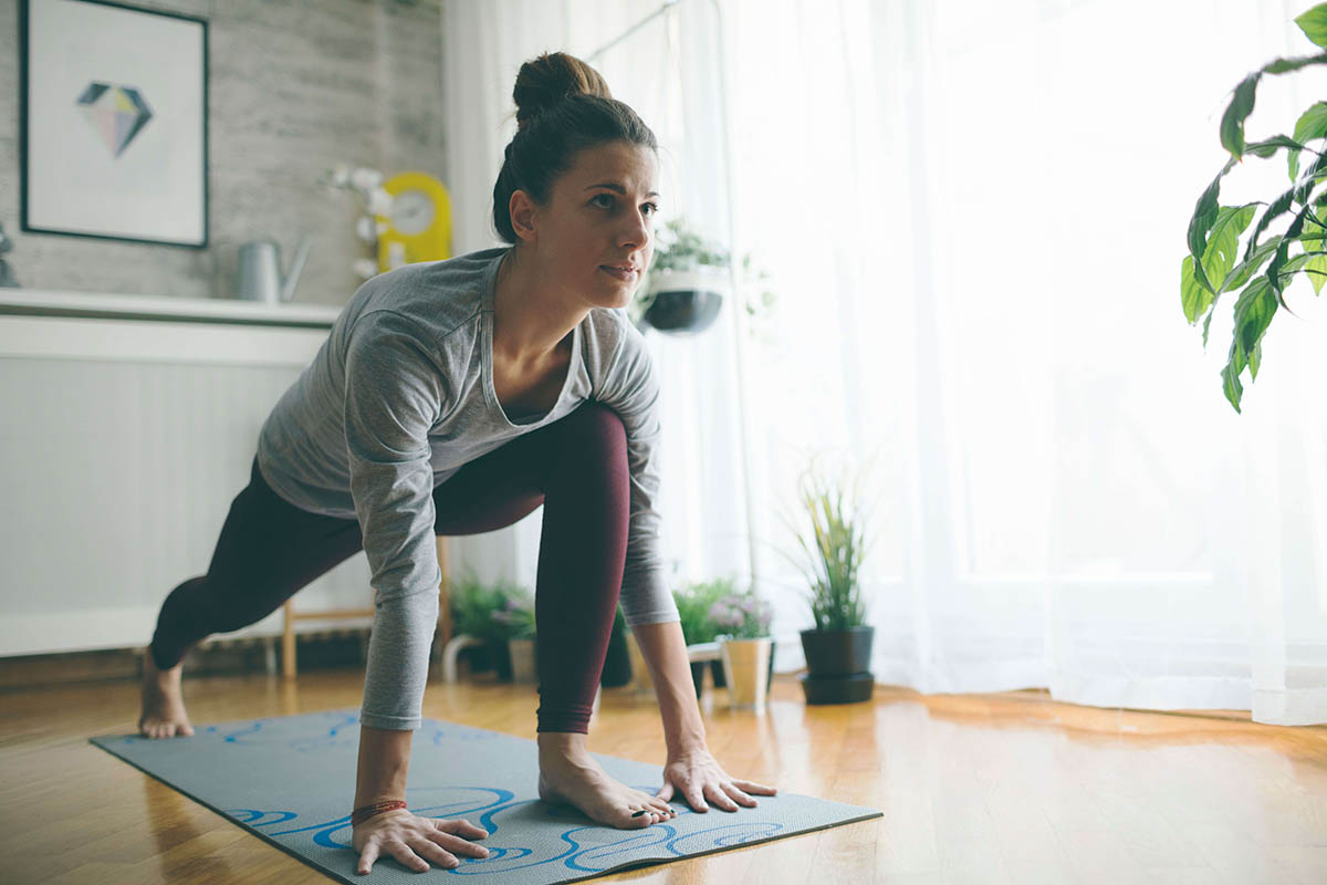Woman wearing athletic clothes doing a yoga pose on a mat.