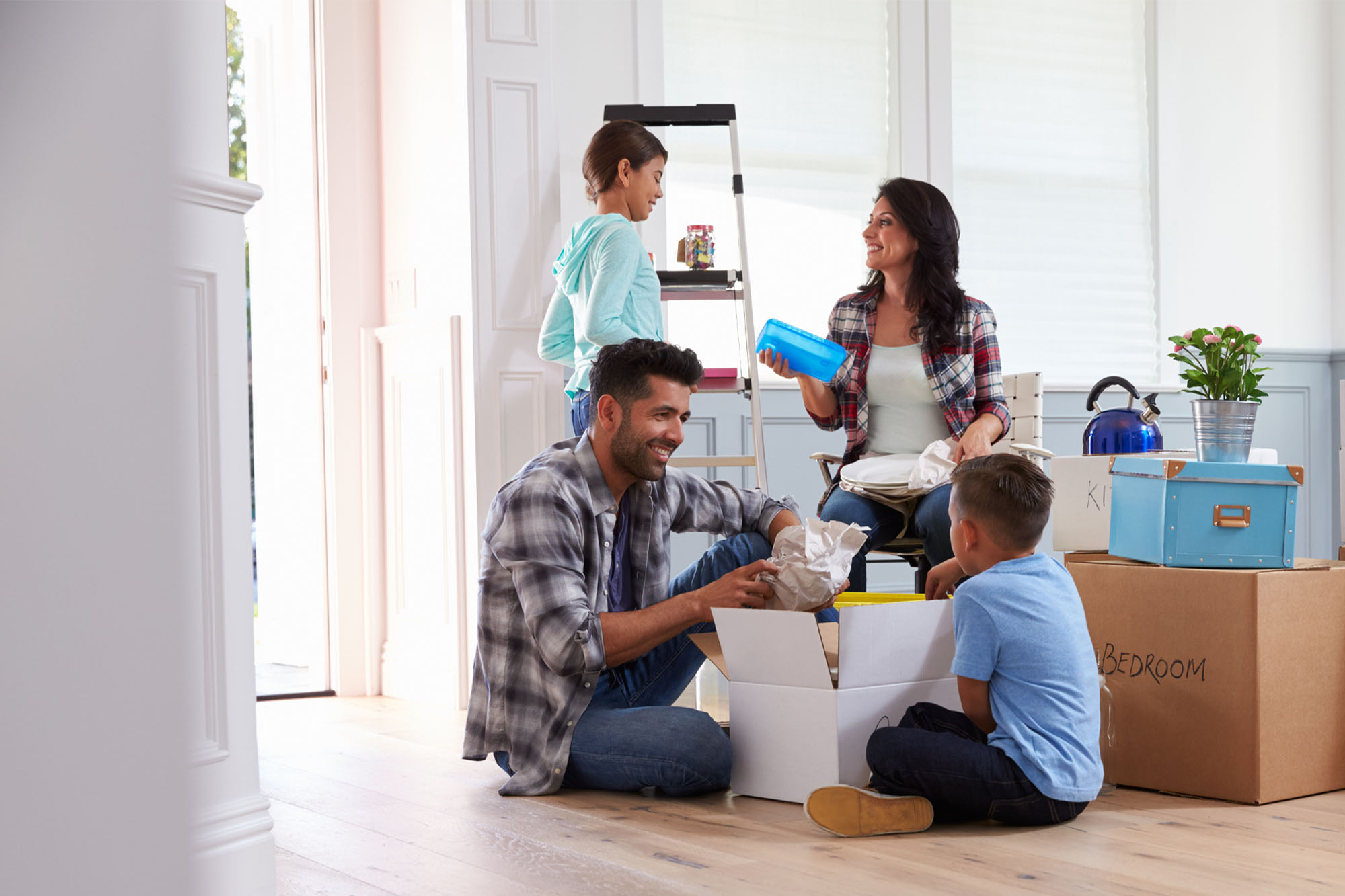 Family unpacking boxes together in their new home, smiling and enjoying the moving-in process.