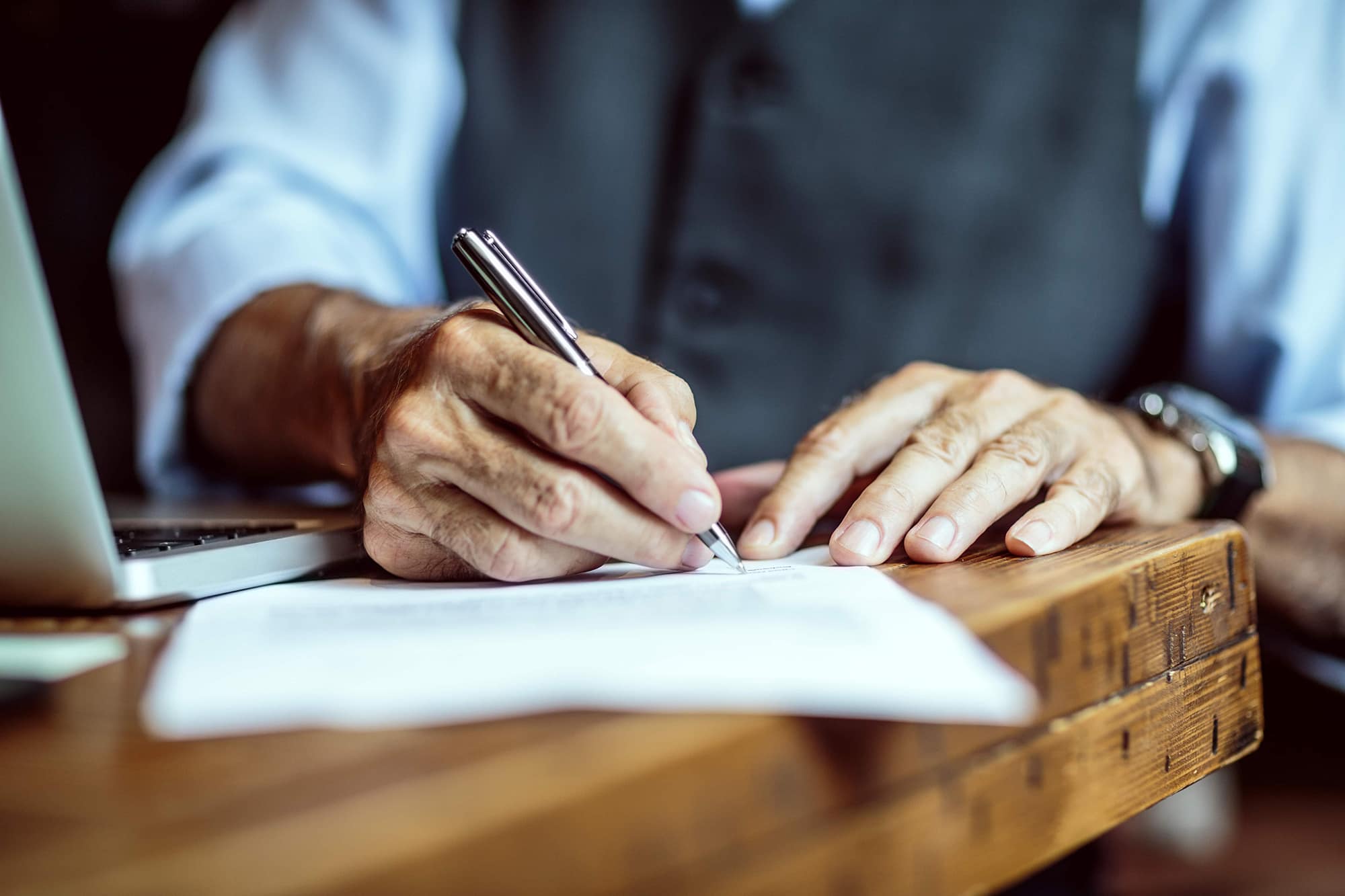 A close up of a guy holding a pen taking notes on a piece of paper. 