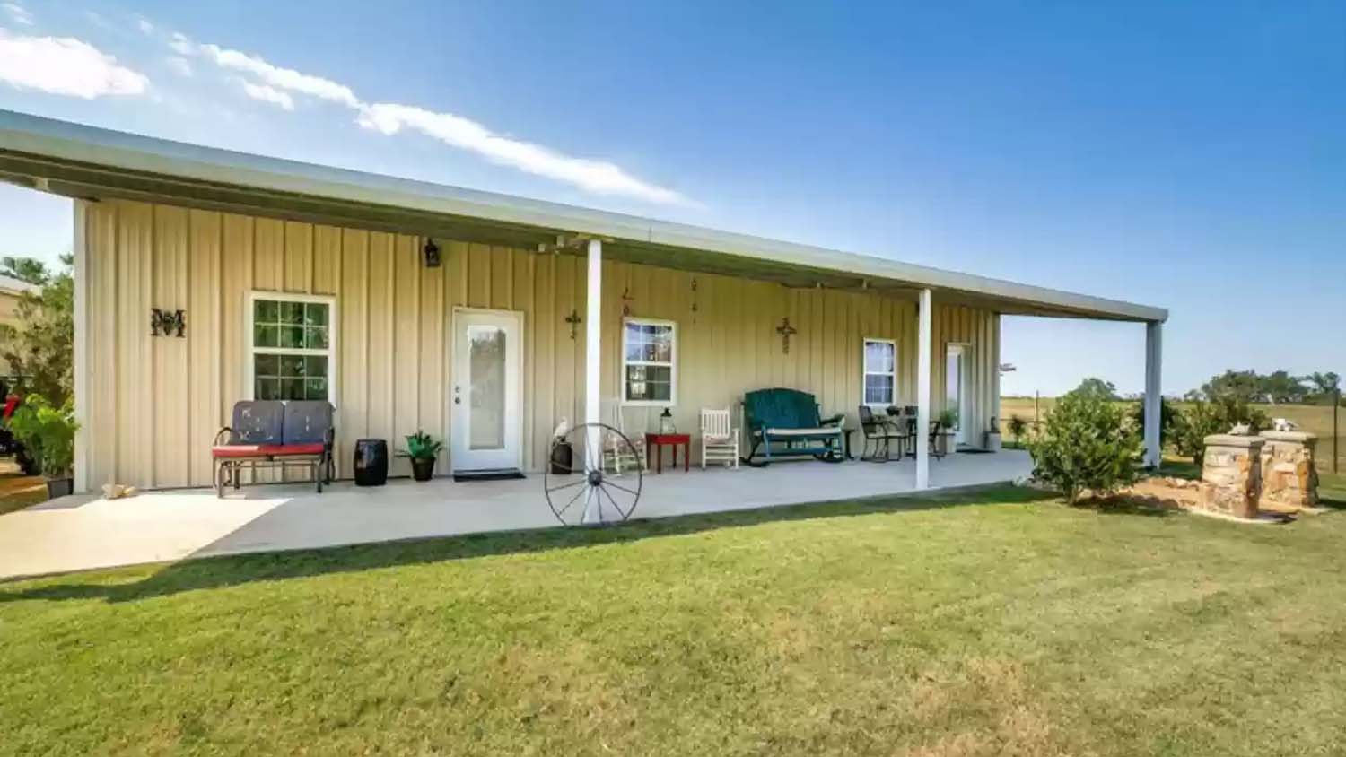 Small home on ranch with chairs and couches on front porch as well as crosses hanging on the wall.