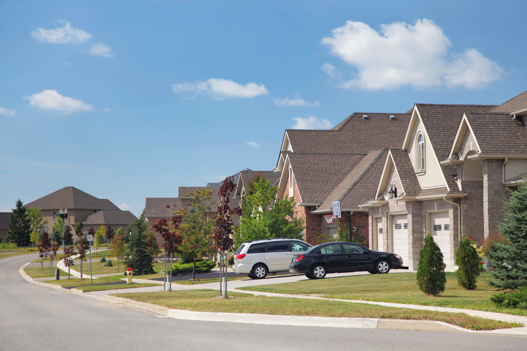 Street view of suburban neighborhood with large brick homes.