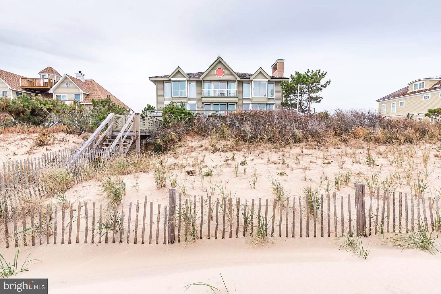 Back view of a tan house, walkway to the beach.