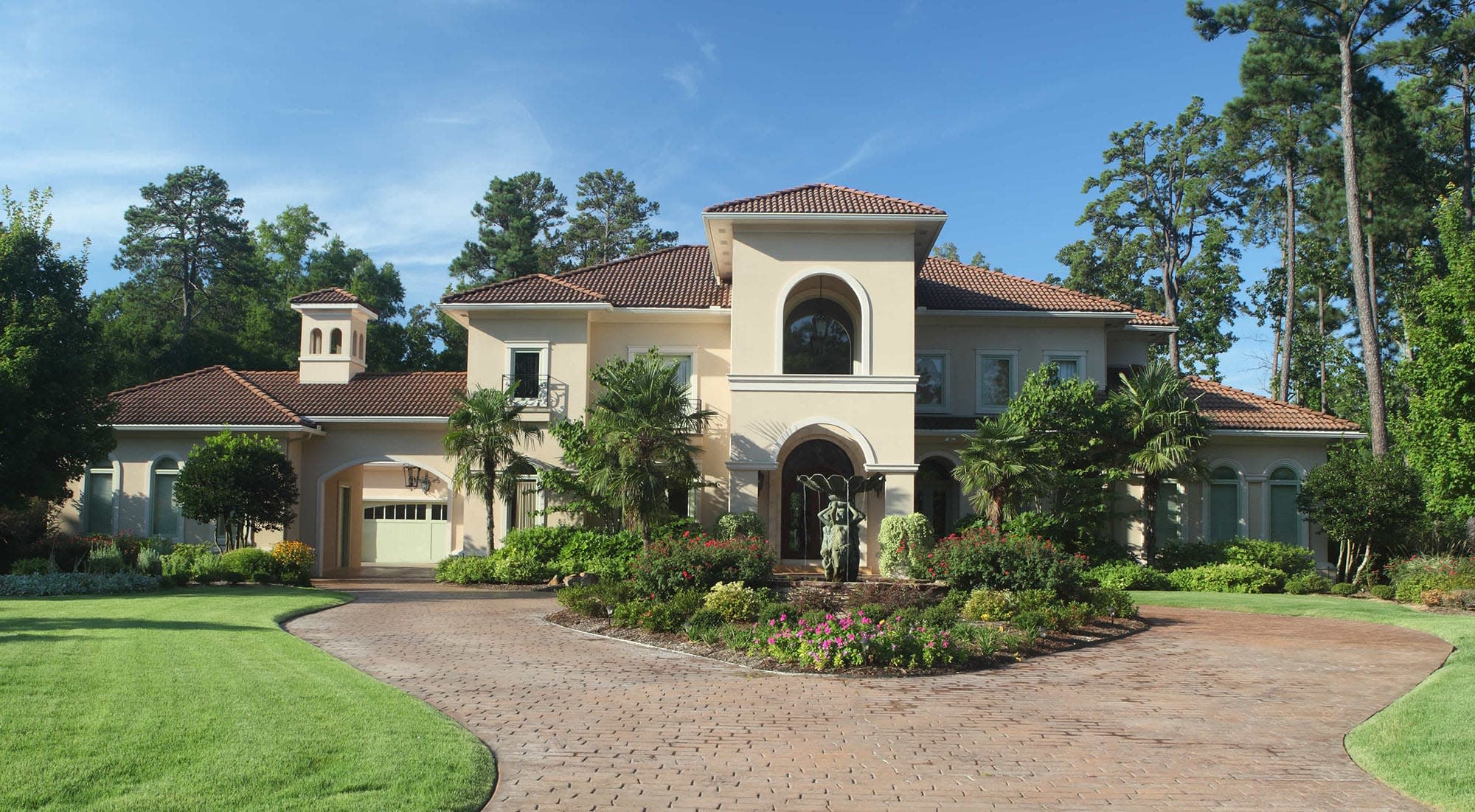 A front view of a house with a circle driveway and wonderful landscaping. 
