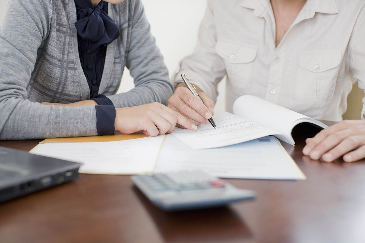 Two people working on a piece of paper with a shot of their hands. 