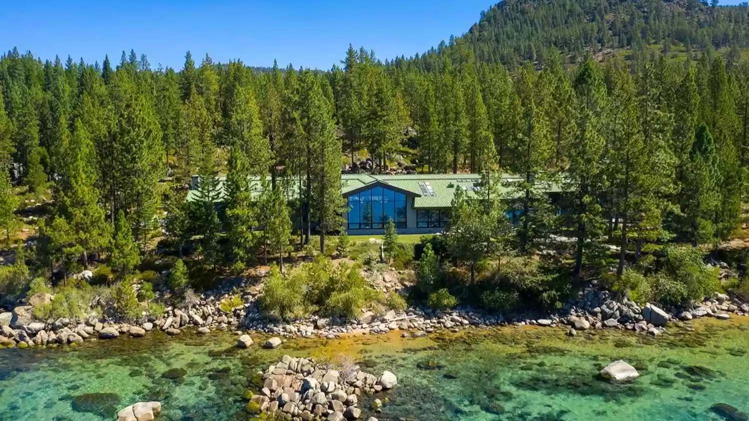 One story waterfront home with a green roof and floor-to-ceiling windows.
