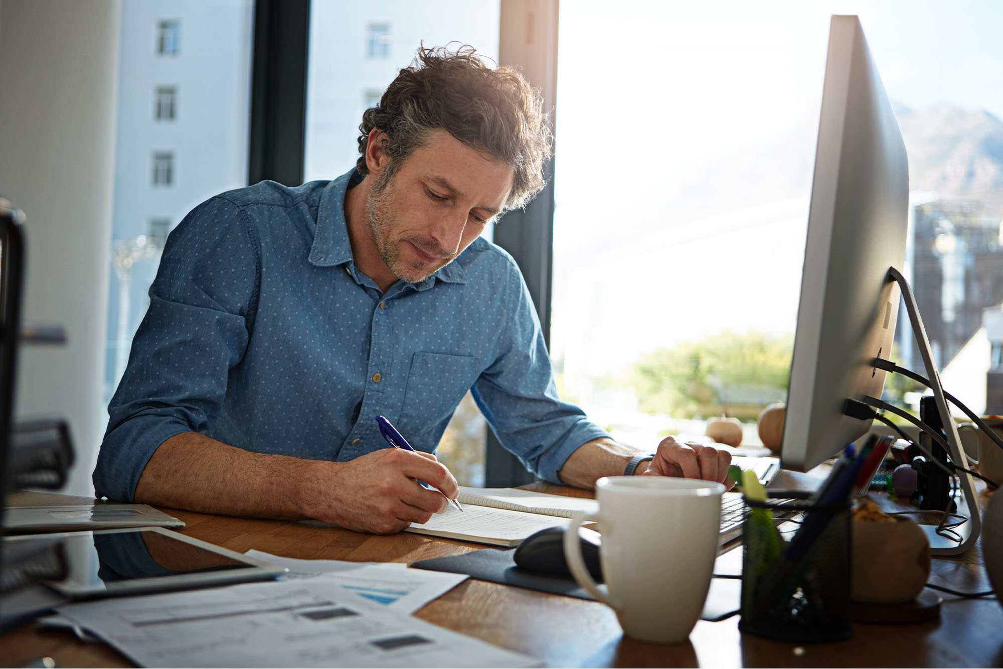 A mortgage loan officer reviews end-of-year paperwork and writes business goals at his desk, planning for the new year.