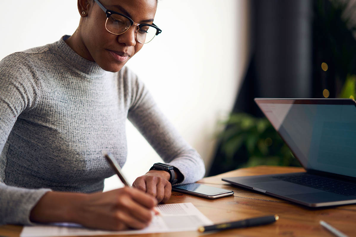 Woman sitting at desk writing on a sheet of paper.