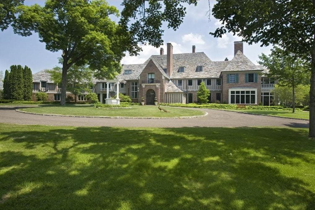 Front view of a brown brick house with a circle driveway. 