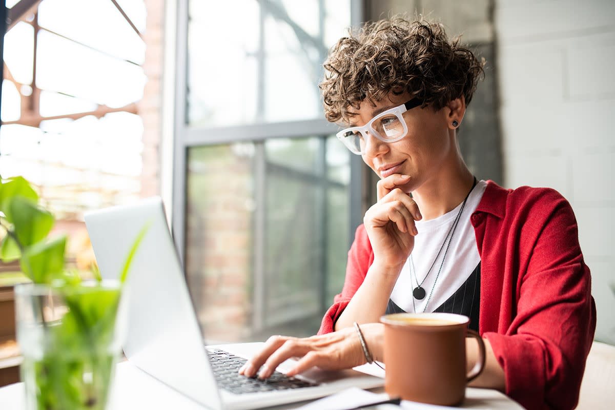 A Woman smirking at her computer in an office setting. 