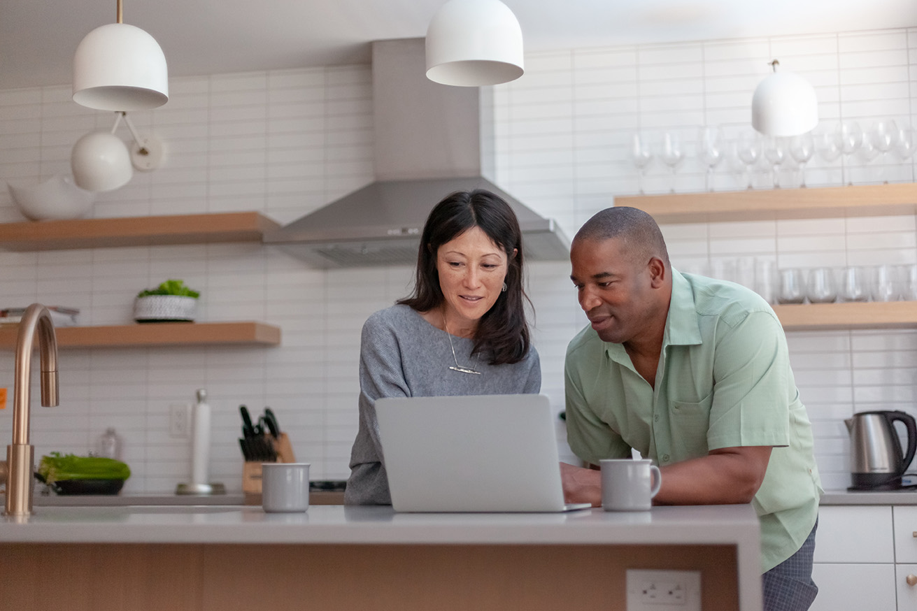 Two people in a kitchen looking at a laptop