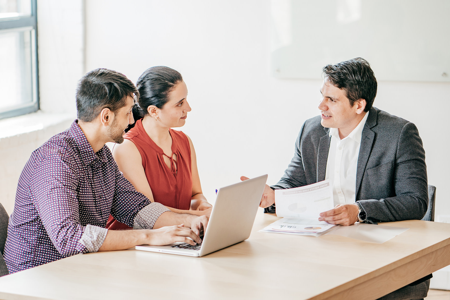 Three people sitting at a table with a laptop