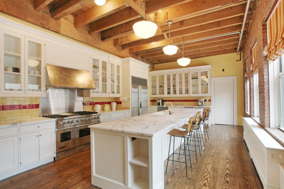 Kitchen with white countertops, white cabinets, and yellow and red backsplash. 