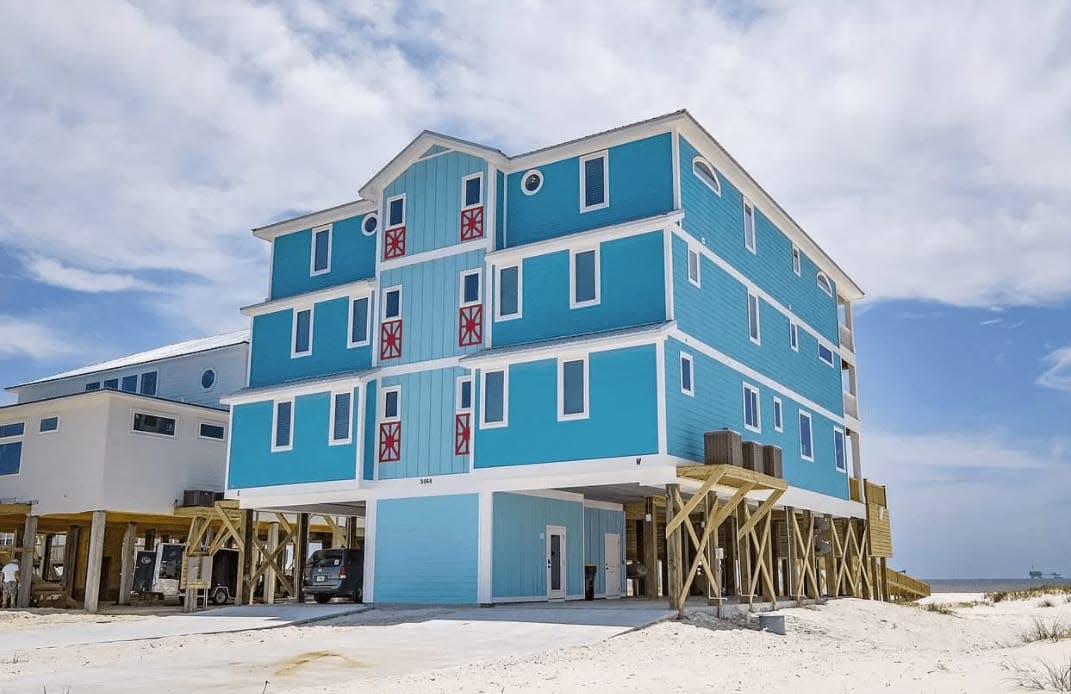 Outside view of a huge three-story blue beach house. 