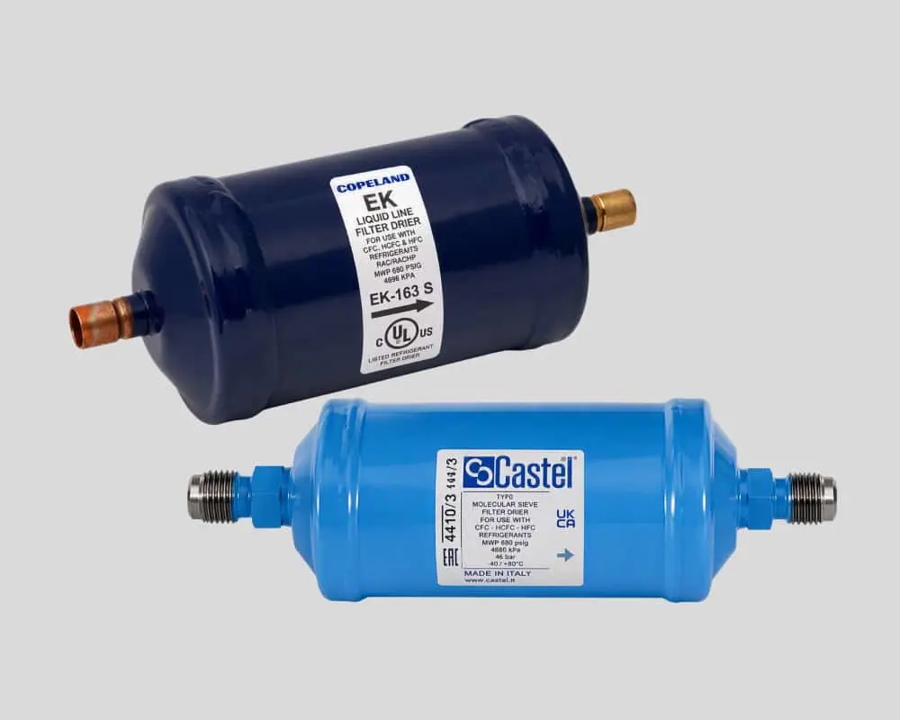 Two refrigerant filter driers, one dark blue Copeland EK model and one light blue Castel model, with copper fittings.
