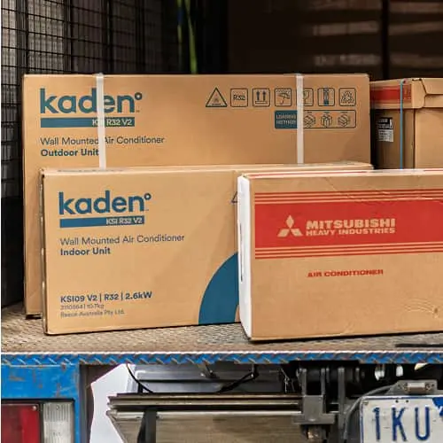 Cardboard boxes of Kaden and Mitsubishi air conditioner units stacked in the back of a truck.