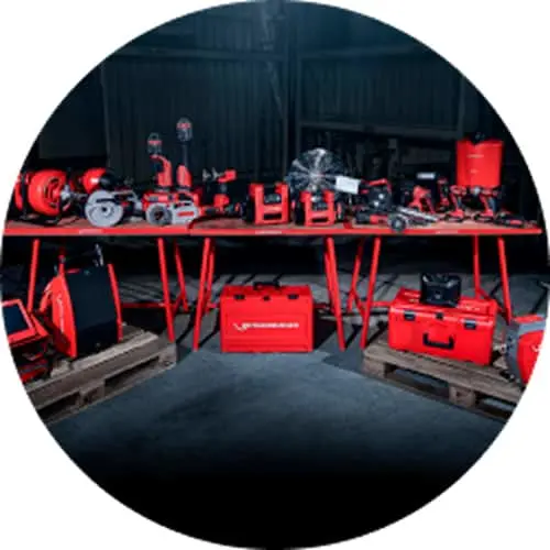 Red power tools and equipment displayed on a red workbench with storage cases underneath in a workshop setting.