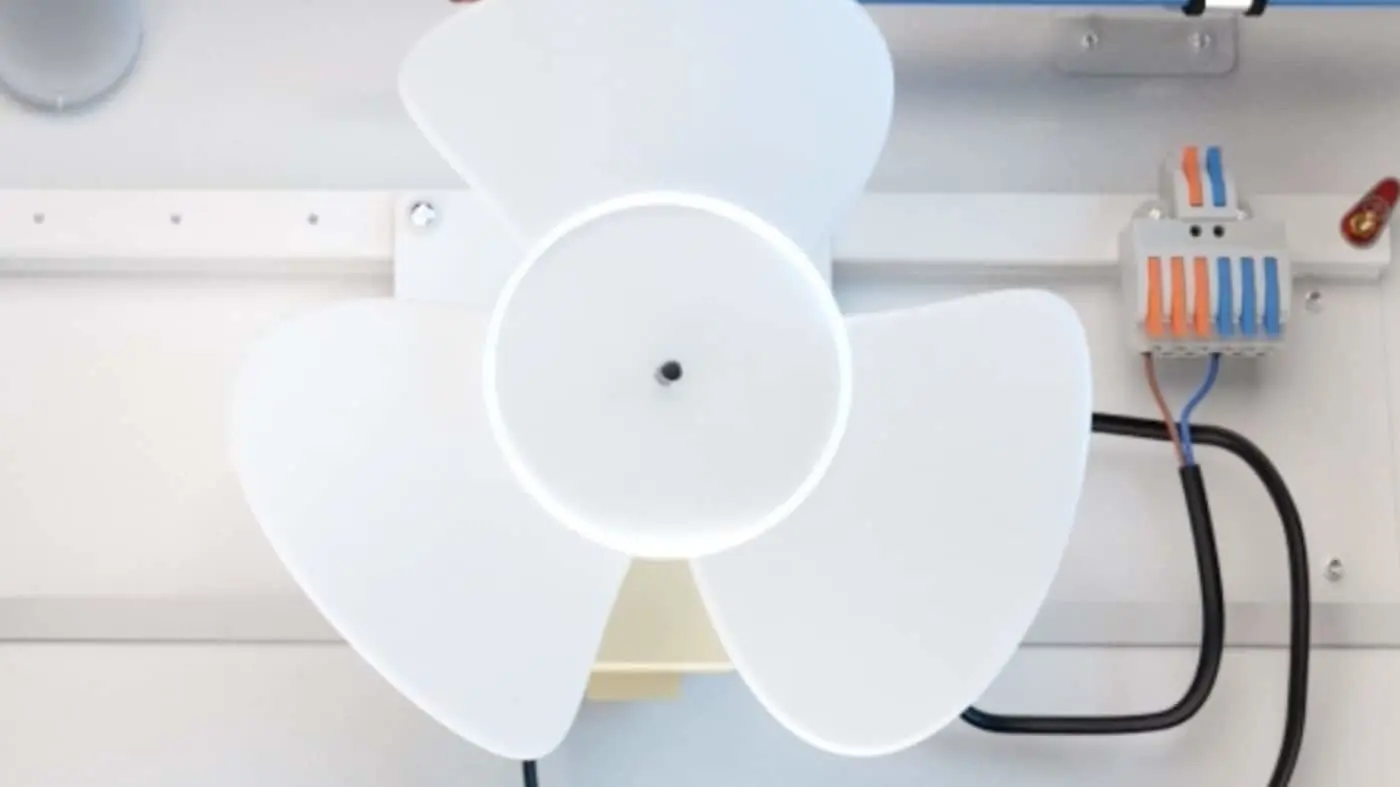 White fan with three blades mounted in-unit with visible wiring and electrical connector.