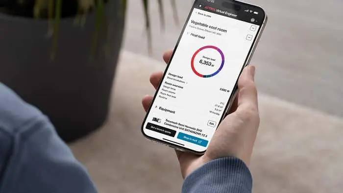 Person holding smartphone displaying app with circular temperature gauge showing 6,953w