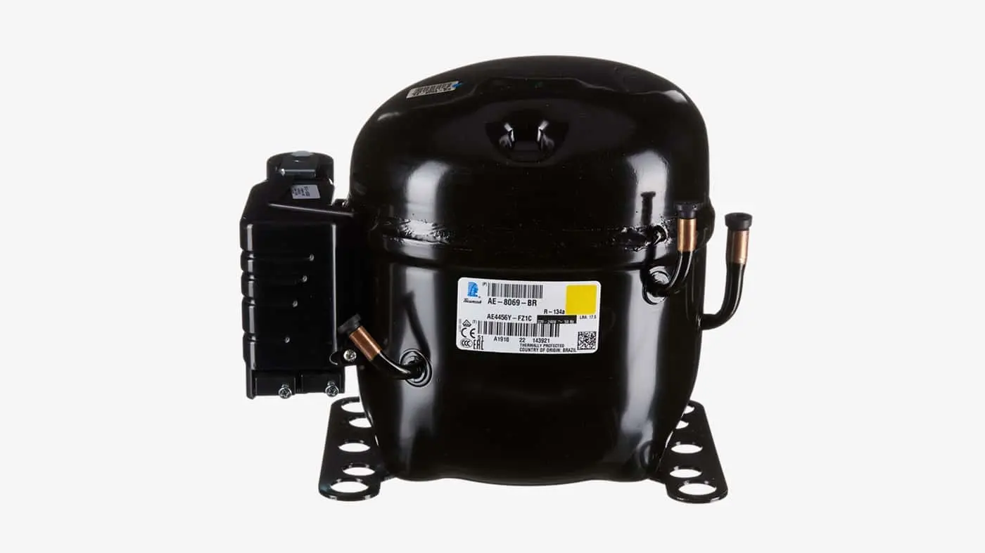 Black refrigeration compressor with copper tubing and white label on front, mounted on base with feet.