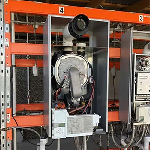 Industrial equipment with circular component and wiring mounted in metal frame on orange shelving unit