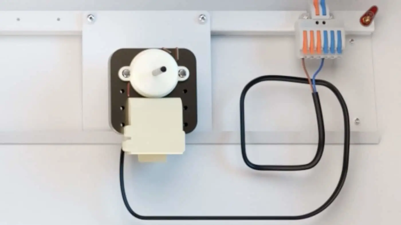 Small motor with white plastic mount connected to wires and a circuit board with orange and blue connectors.