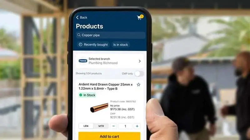 Hand holding smartphone displaying a product page for copper pipe with pricing and add to cart button