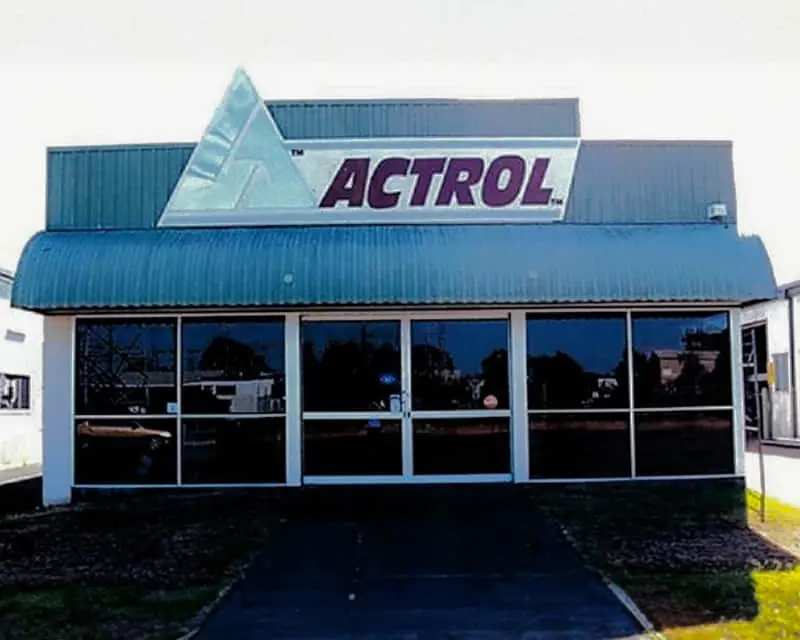 Blue commercial building with ACTROL signage and triangular logo above large glass windows at entrance.