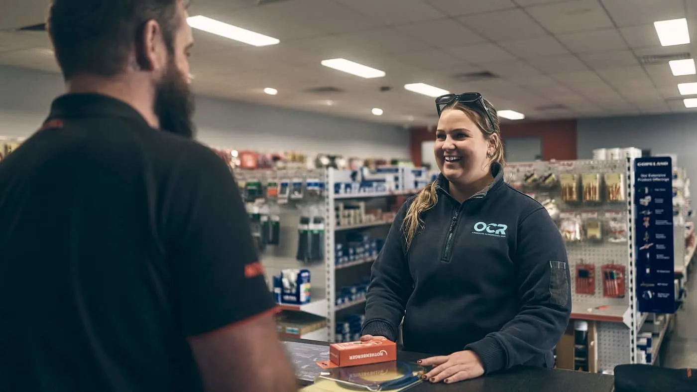 ACTROL staff member assisting a customer at the counter in a store.