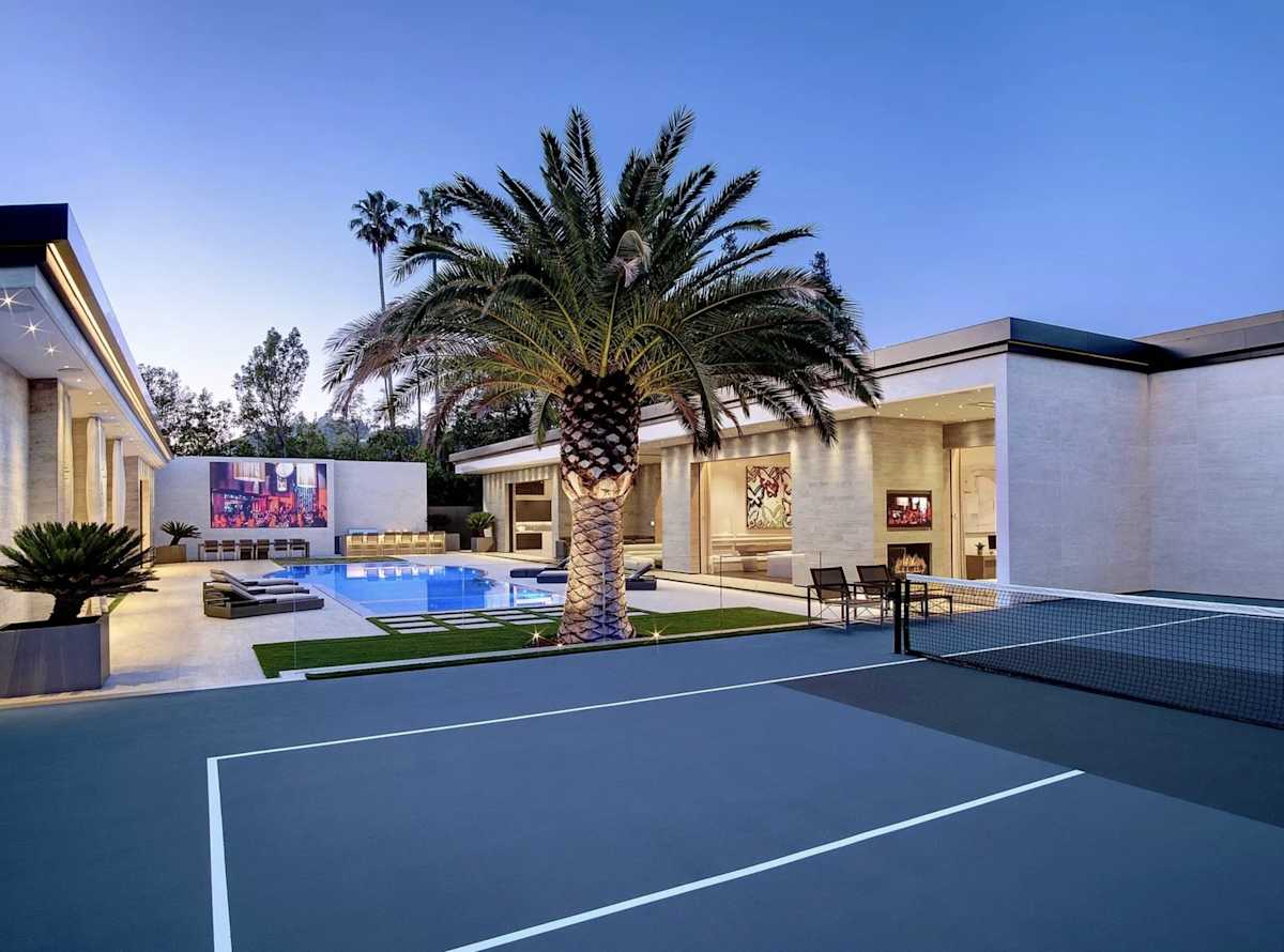 La cancha de tenis está al lado de la piscina.