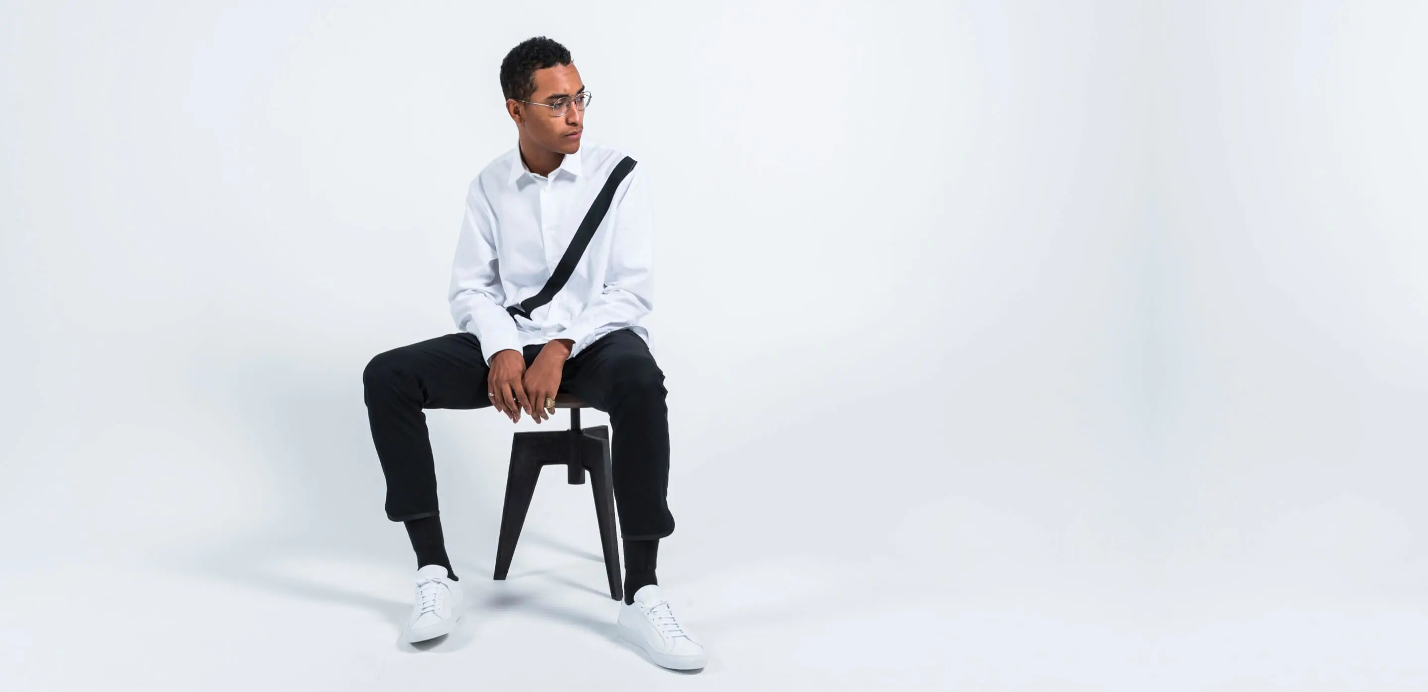 business casual man wearing reign sneakers sitting on stool