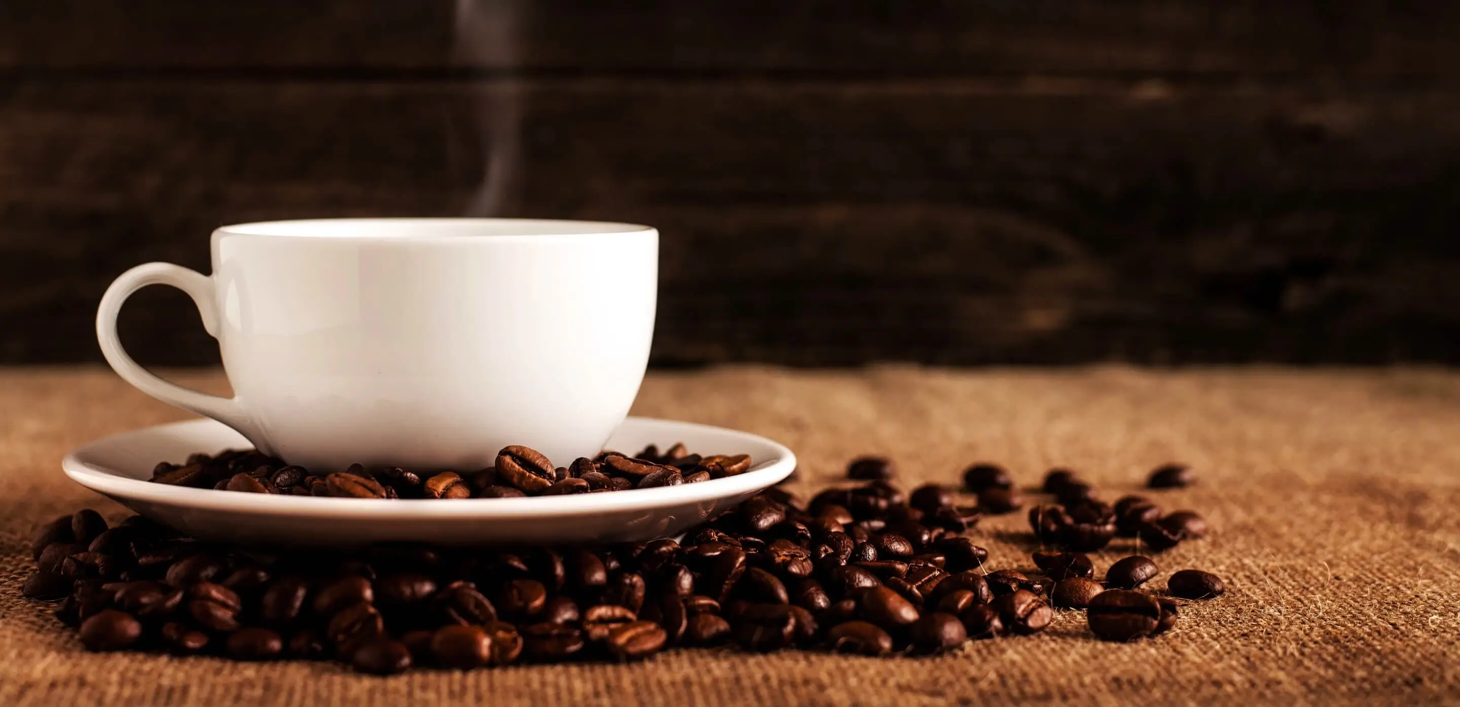 cup of coffee on top of coffee beans