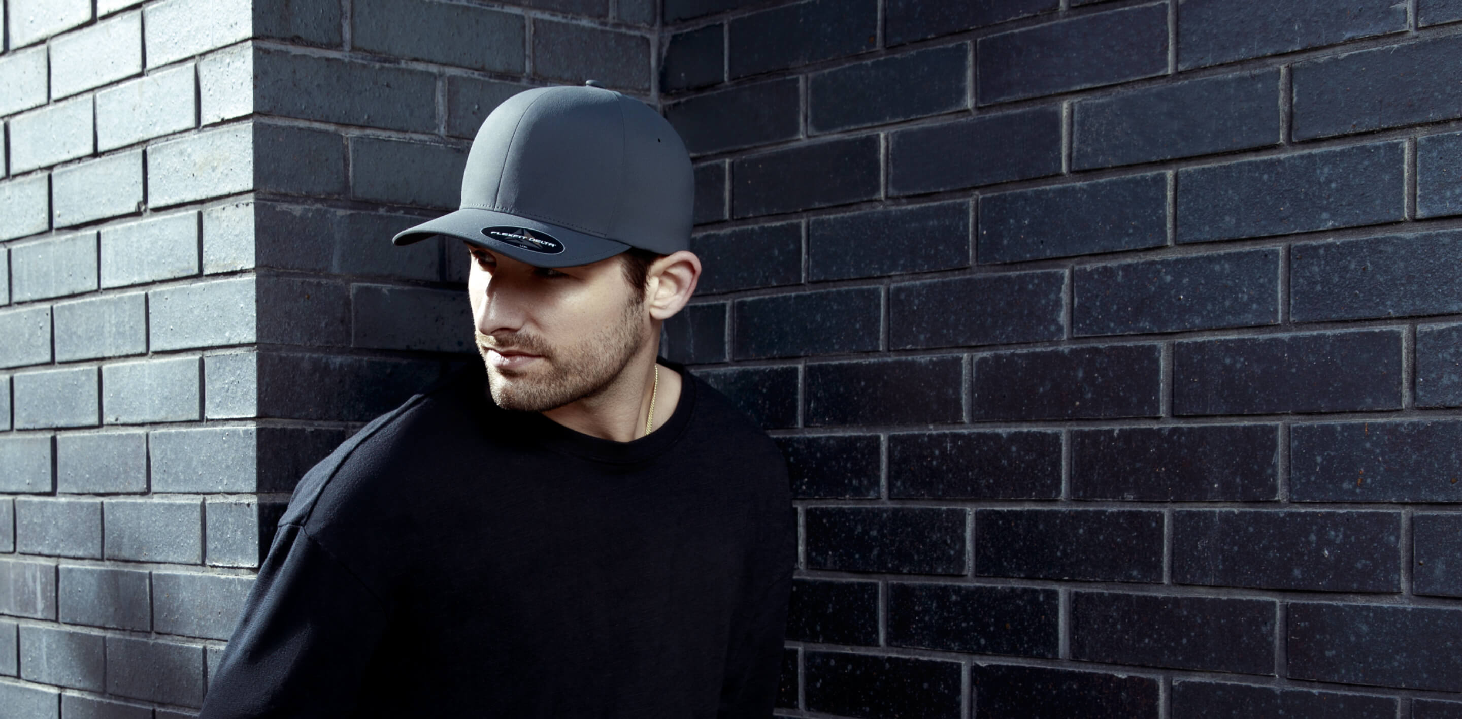standing man wearing black flexfit cap