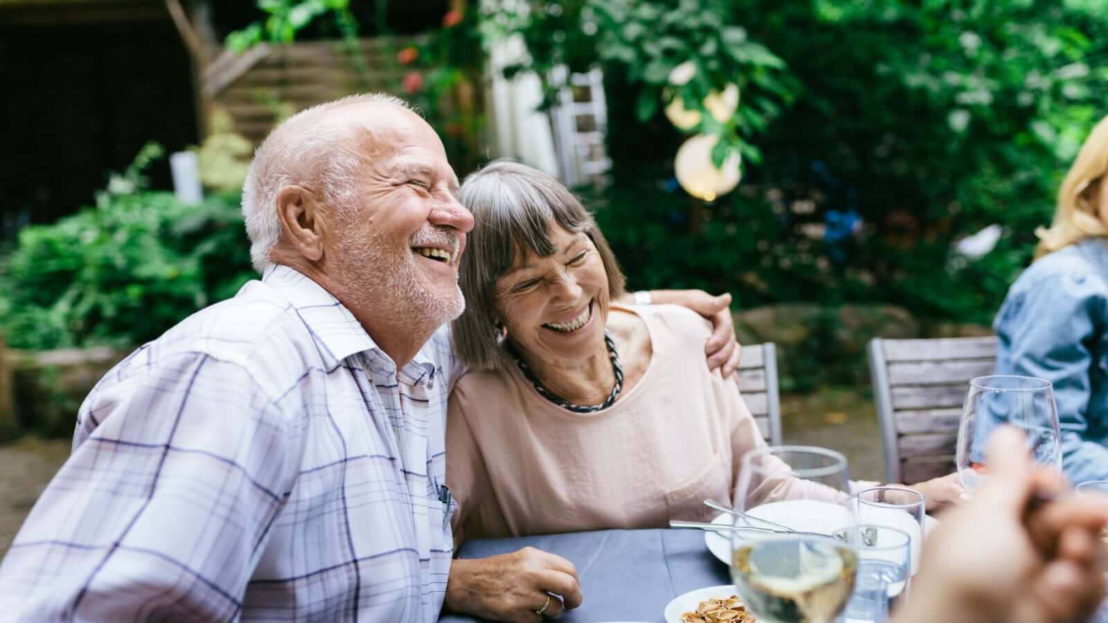 微笑和拥抱在室外餐桌上的老夫妇