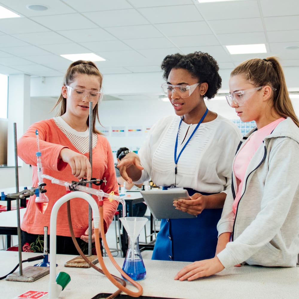 Woman teaching two high school students in science lab