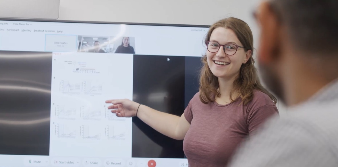 A woman points to a graph of scientific results.