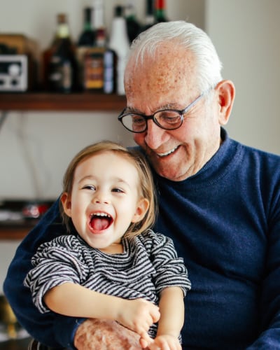 Ein Junge sitzt auf Großvaters Schoss und lacht.